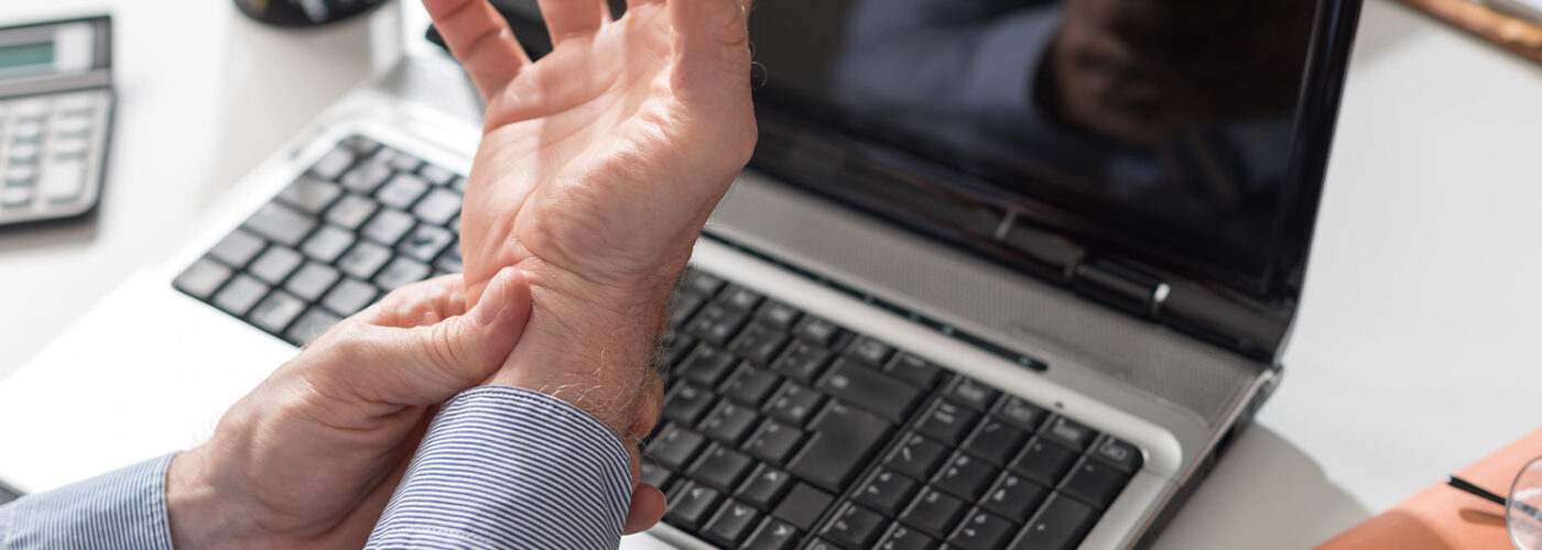 Man sitting at desk holding his wrist