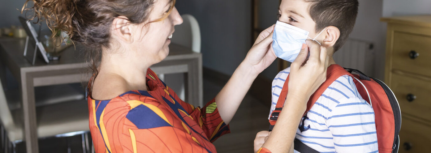 Mother adjusting mask on boy